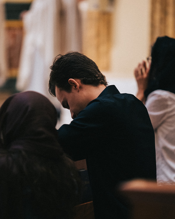 Young man praying in the Guadalupe Shrine pews in preparation to Holy Communion Young man praying in the Guadalupe Shrine pews in preparation to Holy Communion